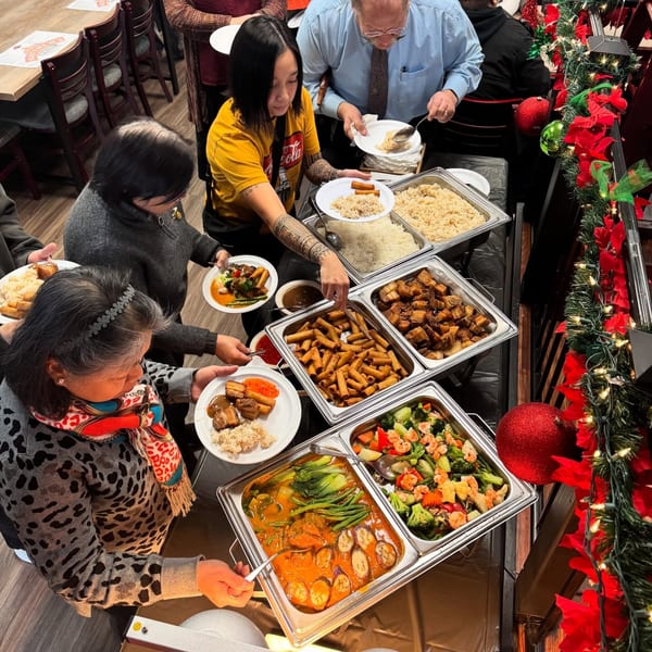 People serving themselves Filipino food from a buffet line at Matthew's Grill, decorated for Christmas.