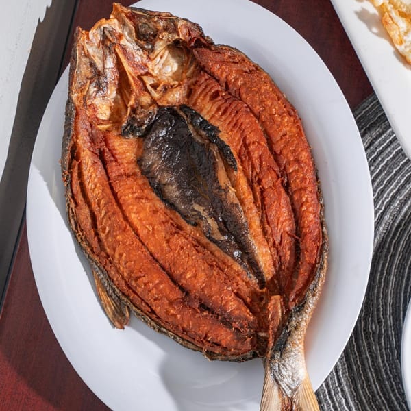A whole fried milkfish, golden brown and crispy, served on a white plate at Matthew's Grill.